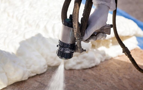 Technician spraying foam insulation on the floor.
