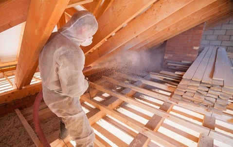Technician spraying foam insulation in an attic.