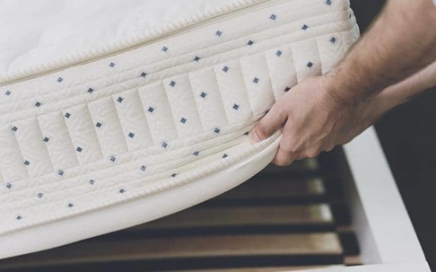 traveler inspecting hotel mattress for bed bugs